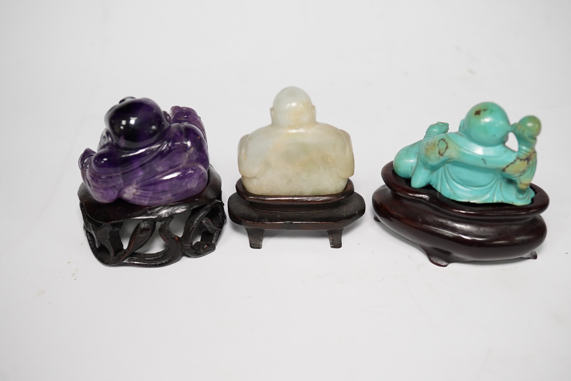 Three Chinese hardstone carvings of Budai, in jadeite, turquoise matrix and amethyst crystal, largest amethyst 4.5cm wide at base (3). Condition - good